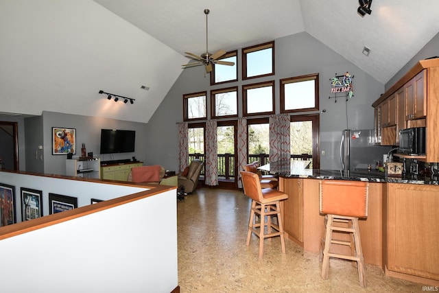 kitchen featuring high vaulted ceiling, track lighting, a kitchen breakfast bar, and ceiling fan