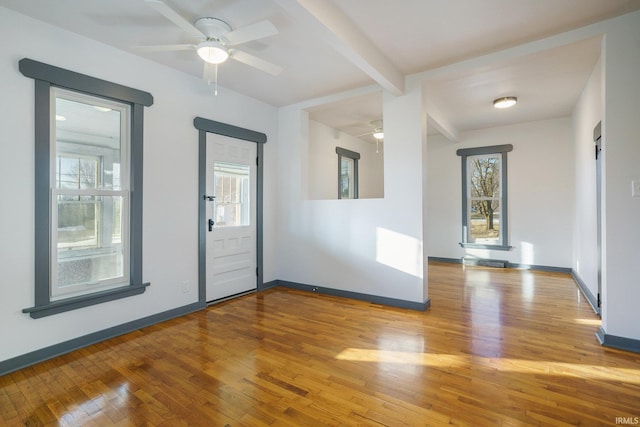 unfurnished room with beam ceiling, ceiling fan, and light wood-type flooring