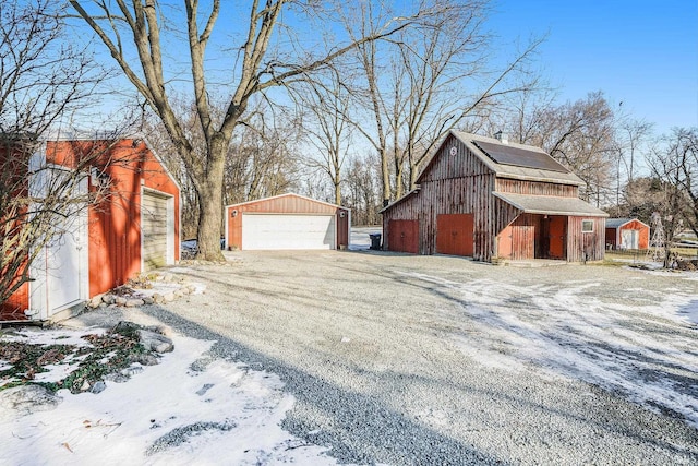 view of snow covered exterior with a garage and an outbuilding