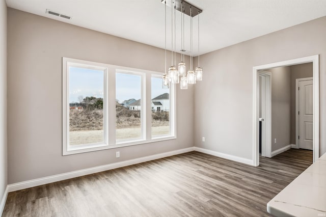 unfurnished dining area with an inviting chandelier and wood-type flooring