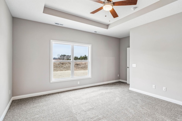 spare room with a tray ceiling, carpet floors, and ceiling fan