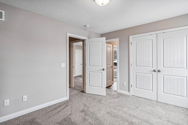 unfurnished bedroom featuring carpet floors, a closet, and a textured ceiling