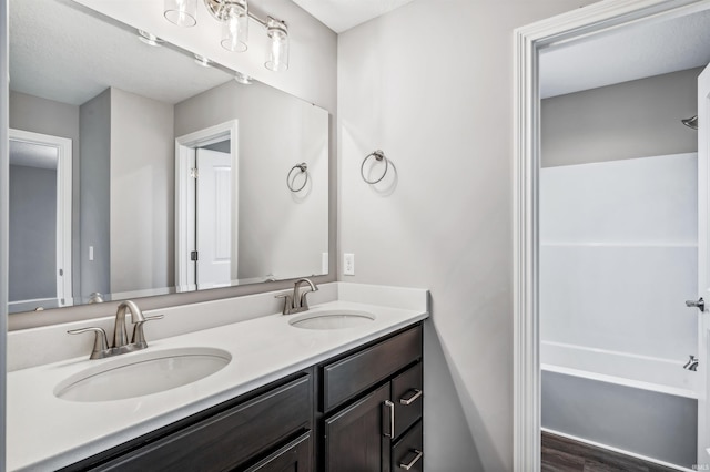 bathroom with vanity, hardwood / wood-style floors, and washtub / shower combination