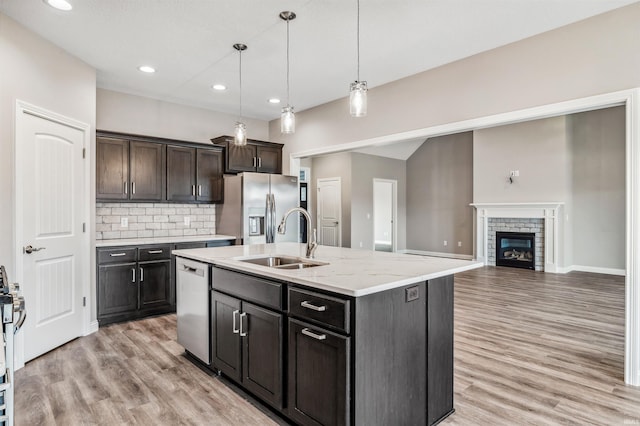 kitchen featuring appliances with stainless steel finishes, decorative light fixtures, sink, a kitchen island with sink, and dark brown cabinets