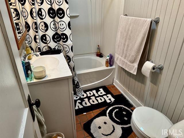 full bathroom featuring vanity, wood walls, toilet, and shower / bath combo with shower curtain