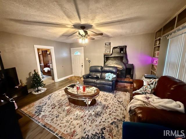 living room with ceiling fan, dark hardwood / wood-style floors, and a textured ceiling