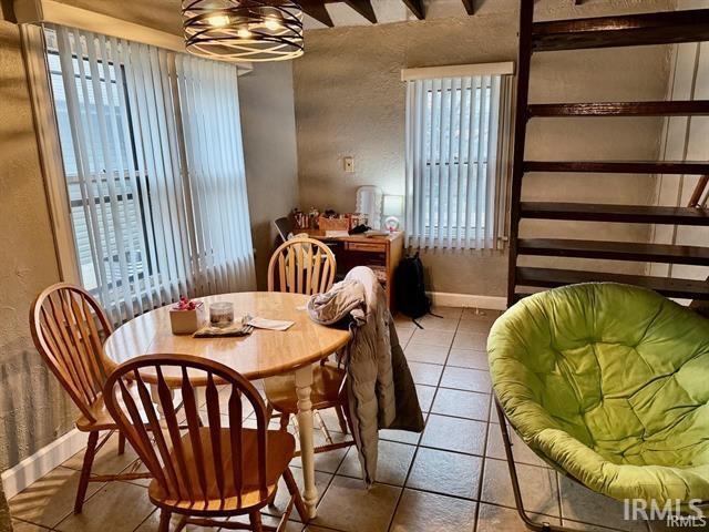 tiled dining space with an inviting chandelier and beamed ceiling