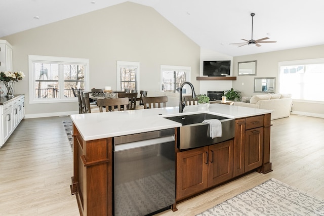 kitchen featuring sink, light hardwood / wood-style flooring, a center island with sink, stainless steel dishwasher, and white cabinets