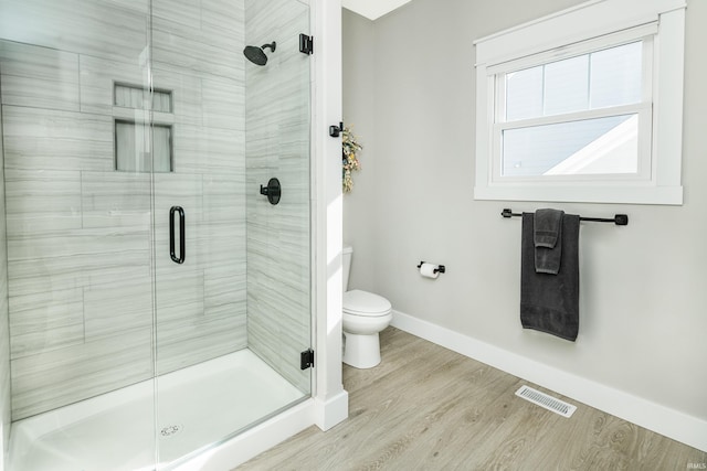 bathroom with wood-type flooring, toilet, and a shower with shower door