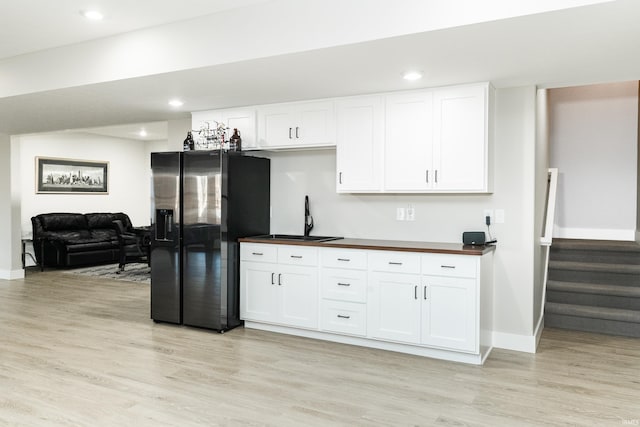 kitchen with sink, stainless steel fridge, light hardwood / wood-style floors, white cabinets, and wood counters