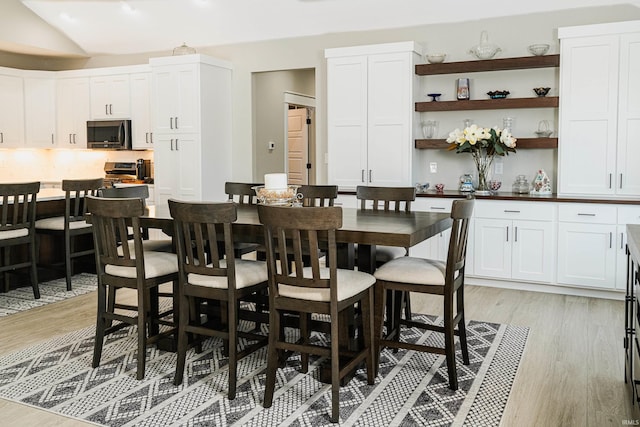 dining space featuring lofted ceiling and light hardwood / wood-style floors