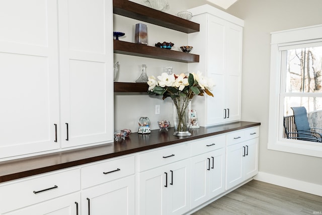 bar with white cabinetry and light hardwood / wood-style floors