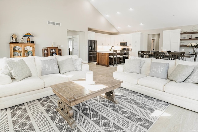 living room featuring high vaulted ceiling and light hardwood / wood-style floors