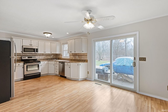 kitchen with tasteful backsplash, white cabinetry, light hardwood / wood-style floors, stainless steel appliances, and crown molding