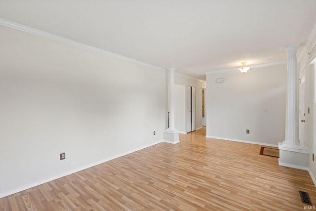 empty room with decorative columns, crown molding, and light hardwood / wood-style floors