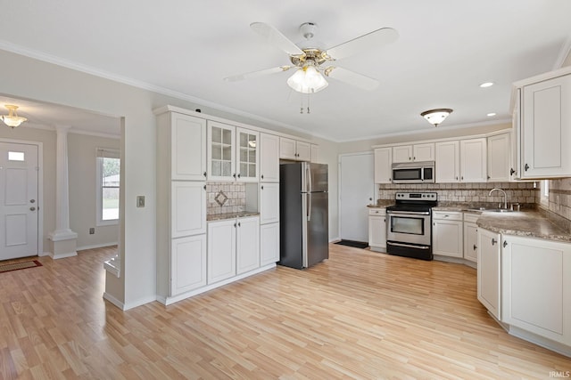 kitchen featuring ornate columns, white cabinetry, light hardwood / wood-style flooring, appliances with stainless steel finishes, and backsplash