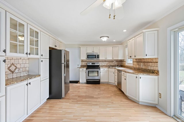 kitchen featuring sink, appliances with stainless steel finishes, light stone counters, ornamental molding, and white cabinets