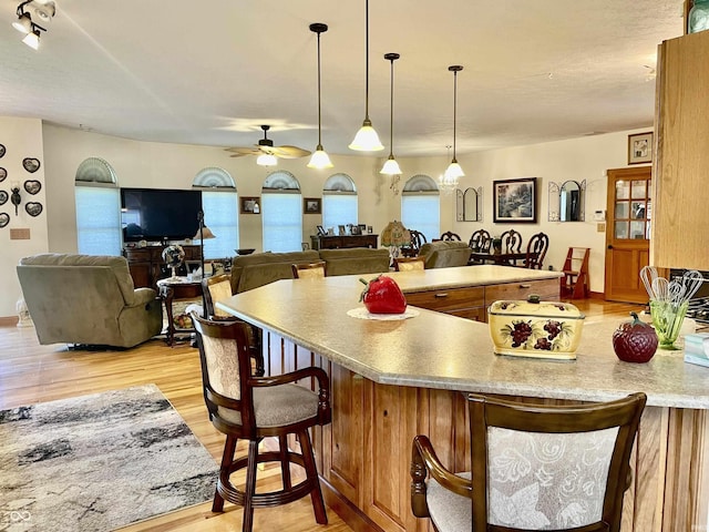 kitchen featuring ceiling fan, a breakfast bar area, light hardwood / wood-style floors, and decorative light fixtures