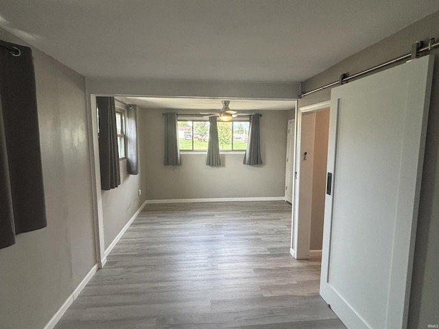 hallway featuring a barn door and light hardwood / wood-style flooring