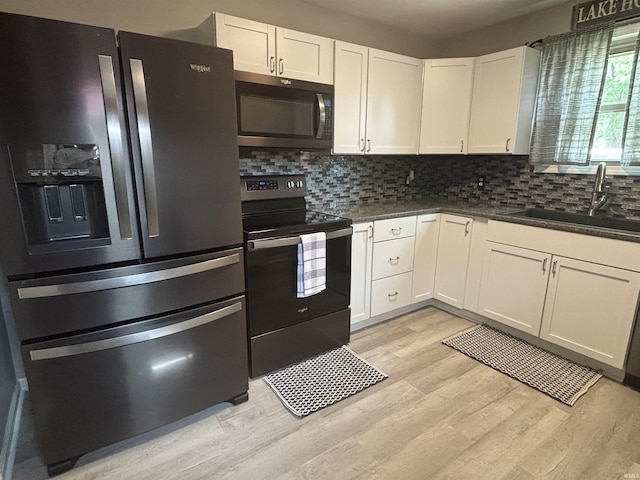 kitchen with electric stove, white cabinetry, sink, stainless steel fridge with ice dispenser, and light hardwood / wood-style flooring