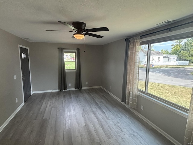 spare room featuring ceiling fan, wood-type flooring, and a textured ceiling