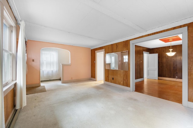 spare room with carpet, a baseboard heating unit, and wooden walls