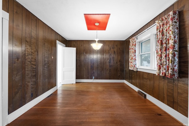 empty room with hardwood / wood-style flooring and wooden walls