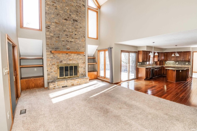 unfurnished living room featuring dark colored carpet, sink, a fireplace, and built in shelves