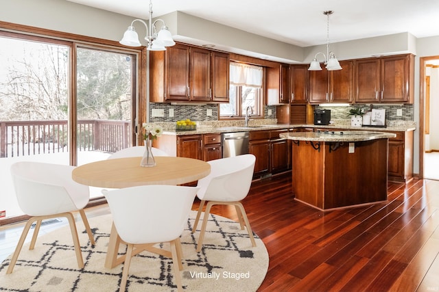 kitchen featuring hanging light fixtures, dark wood-type flooring, a center island, and dishwasher