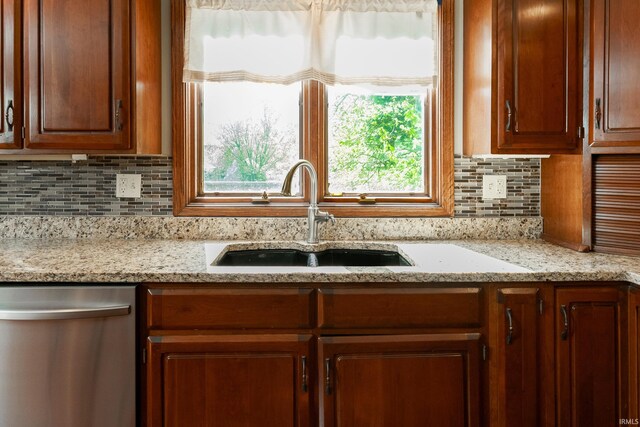 kitchen with sink, decorative backsplash, stainless steel dishwasher, and light stone countertops