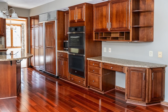 kitchen featuring an inviting chandelier, multiple ovens, decorative light fixtures, and dark wood-type flooring