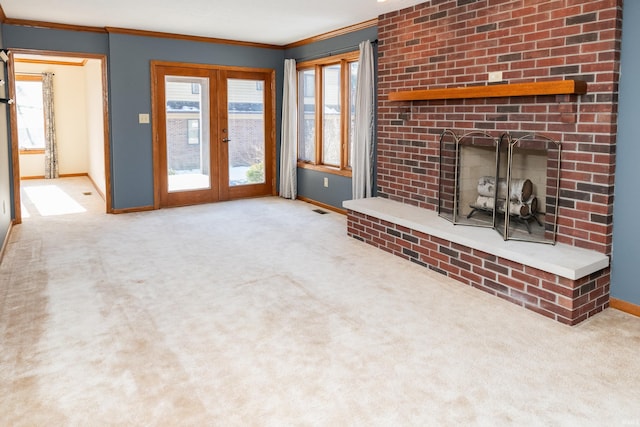 unfurnished living room featuring ornamental molding, a brick fireplace, light colored carpet, and french doors