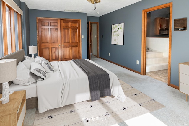 carpeted bedroom featuring connected bathroom, a textured ceiling, and a closet