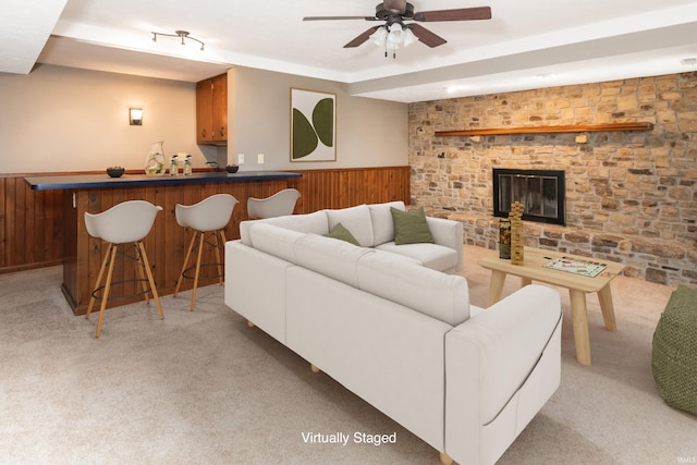 carpeted living room with ceiling fan, bar, and a brick fireplace