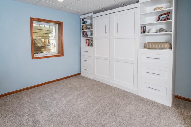 unfurnished bedroom with light colored carpet, a drop ceiling, and a closet