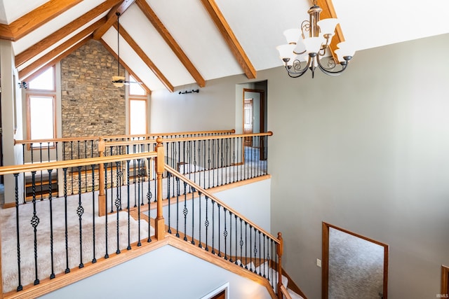 staircase with beam ceiling, a notable chandelier, and high vaulted ceiling