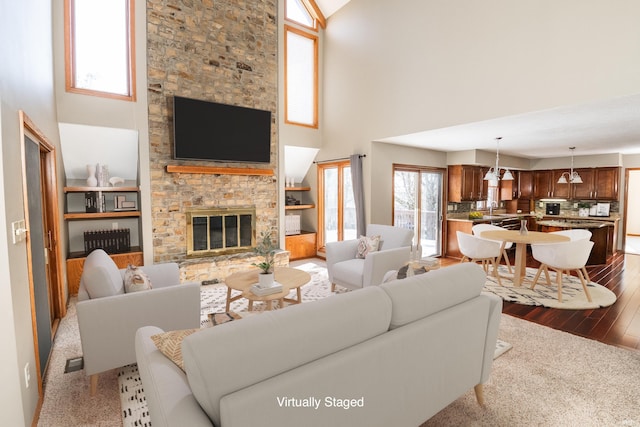 living room featuring light hardwood / wood-style flooring, a towering ceiling, and a fireplace