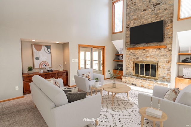 carpeted living room with a stone fireplace and a high ceiling