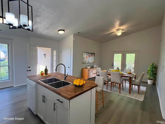 kitchen with wood counters, sink, a center island with sink, dishwasher, and white cabinets