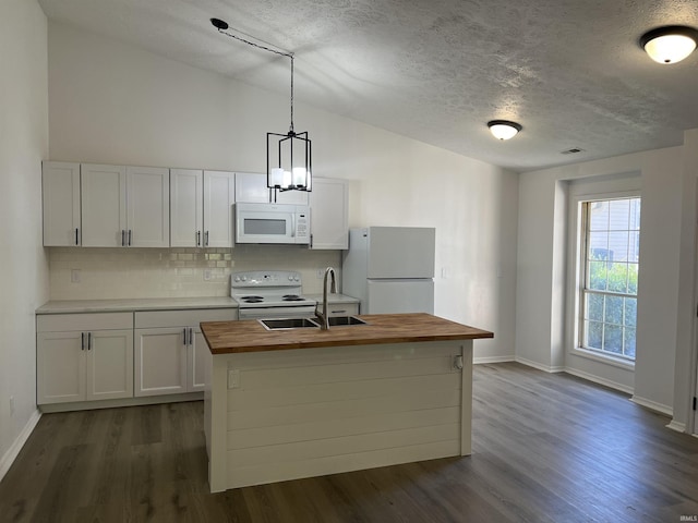 kitchen with butcher block counters, an island with sink, pendant lighting, white appliances, and white cabinets