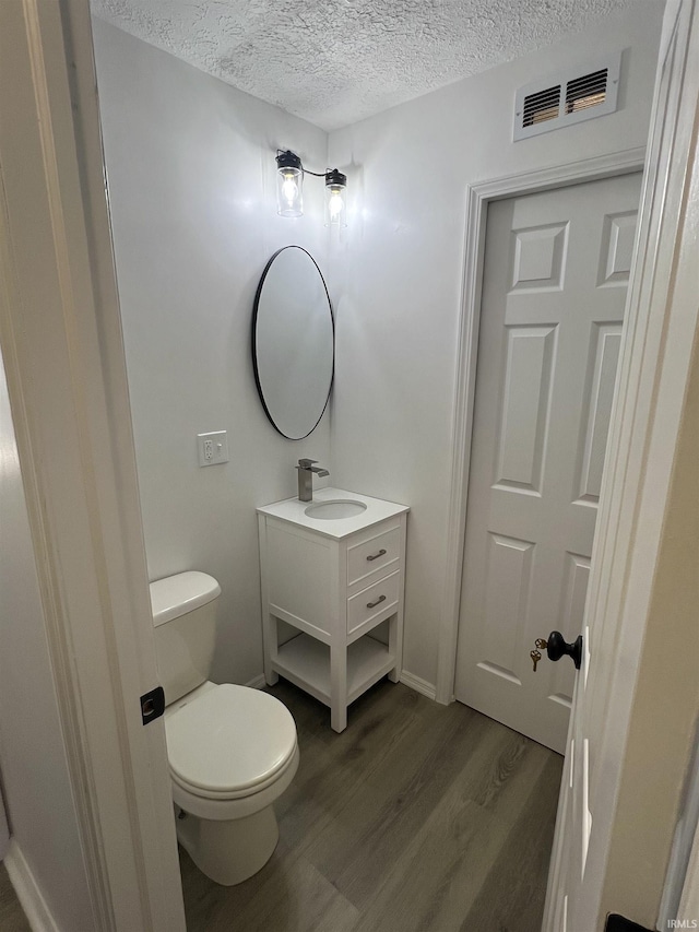 bathroom featuring vanity, hardwood / wood-style floors, a textured ceiling, and toilet