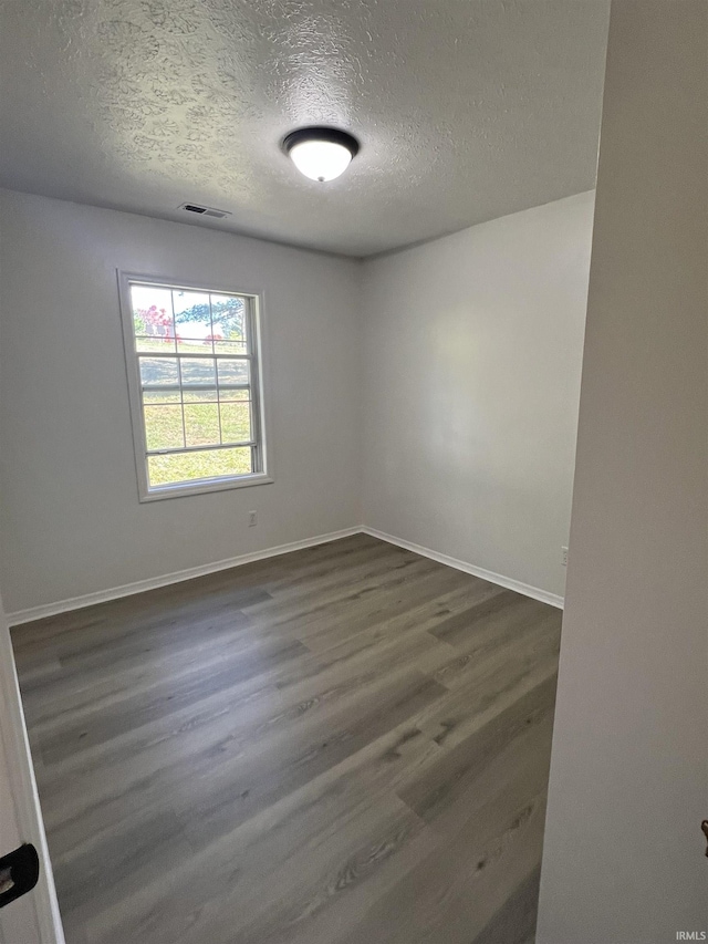 unfurnished room with dark hardwood / wood-style flooring and a textured ceiling