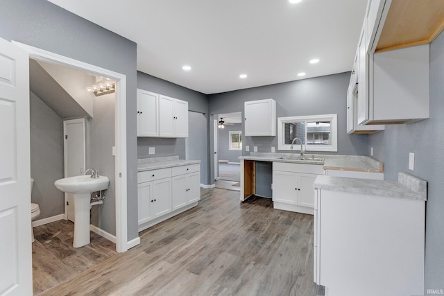 kitchen with ceiling fan, sink, white cabinets, and light wood-type flooring