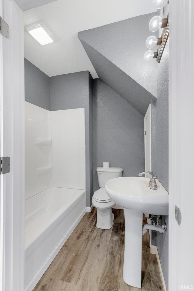 bathroom with shower / bathing tub combination, hardwood / wood-style flooring, and toilet