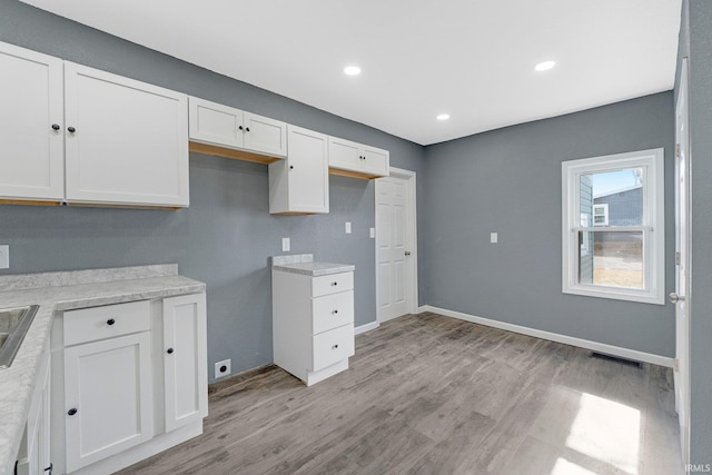 kitchen featuring white cabinetry, sink, and light hardwood / wood-style flooring