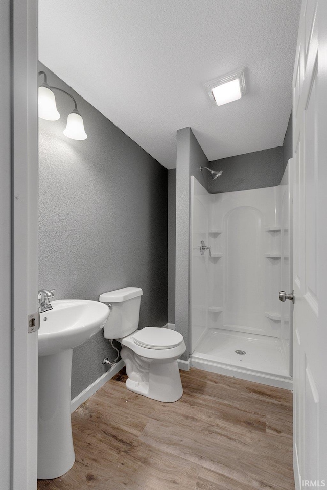 bathroom featuring sink, hardwood / wood-style flooring, a shower, a textured ceiling, and toilet