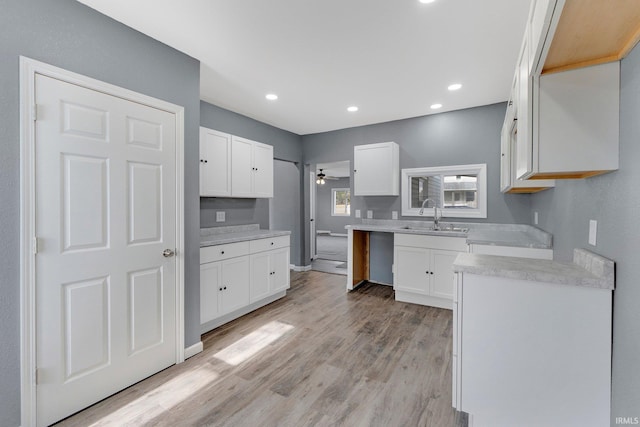 kitchen with white cabinetry, ceiling fan, sink, and light hardwood / wood-style flooring