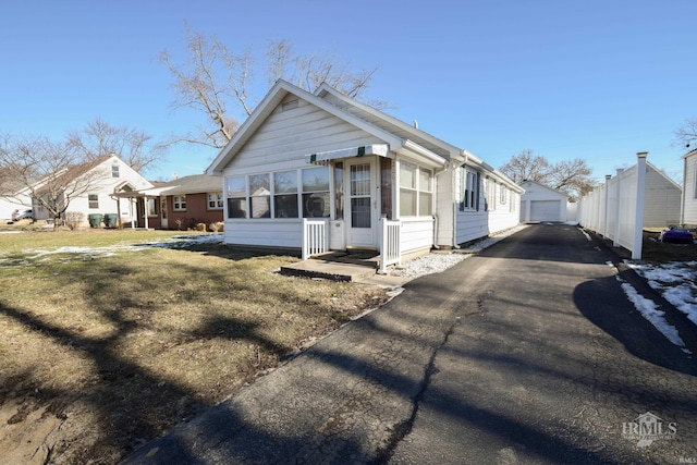 view of front of property featuring a garage, an outbuilding, and a front lawn