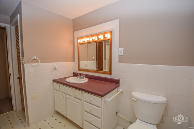 bathroom featuring vanity, toilet, and tile walls