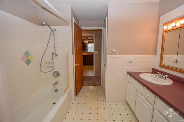 bathroom with tiled shower / bath, vanity, and tile walls